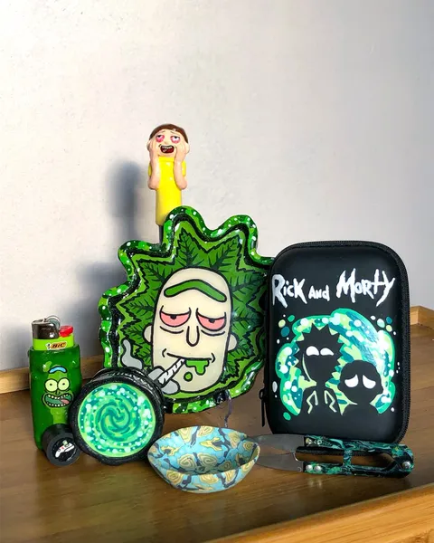 Kit temático de Rick and Morty pintado à mão sobre uma mesa de madeira, bandeja verde do Rick, dichavador com portal, isqueiro do Pickle Rick, estojo preto pintado e um pequeno boneco do Morty.